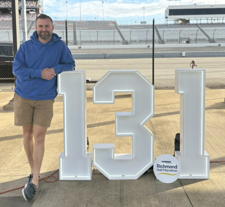 David beside the 13.1 sign at the Richmond Half Marathon